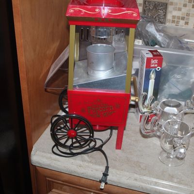 Nostalgia Electrics tabletop popcorn maker in a vintage cart style, shown alongside glass moose mugs and other household items.