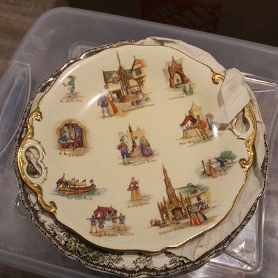 Sale Photo Thumbnail #35: Vintage decorative porcelain plate featuring historical English scenes, with a scalloped gold-trimmed rim and integrated handles.