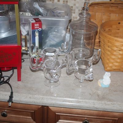 Assorted household items including a vintage-style tabletop popcorn maker, clear glass moose mugs, a glass apothecary jar, and woven...