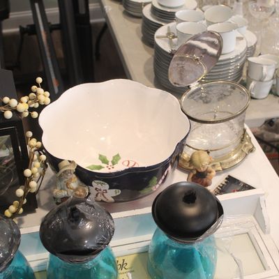 Assorted tabletop decor and tableware, featuring a festive holiday bowl, a glass ice bucket with a metal lid, and various glassware and...