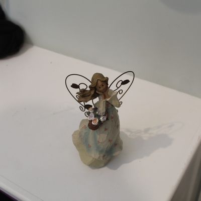 Sale Photo Thumbnail #9: Small resin angel figurine with wire wings, holding a basket of flowers, in good condition.