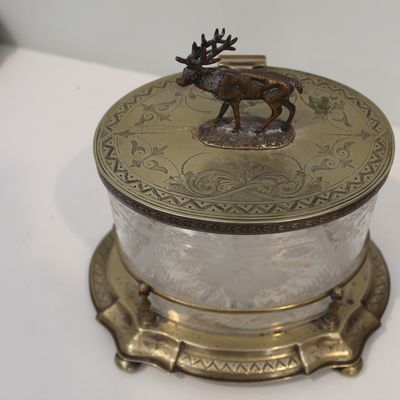 Sale Photo Thumbnail #21: Antique glass and brass biscuit jar featuring an etched glass body, an ornate brass base, and a hinged lid topped with a detailed stag finial.