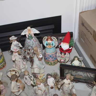Collection of Jim Shore Heartwood Creek figurines, featuring various angels and a Santa Claus, alongside framed folk art prints.