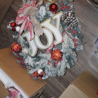 Sale Photo Thumbnail #26: Flocked Christmas wreath featuring a wooden "JOY" sign, red ornaments, pinecones, berries, and a striped ribbon bow.