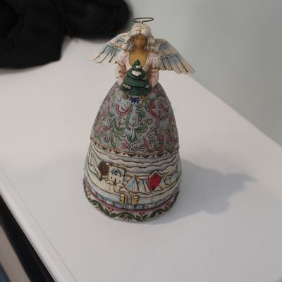 Sale Photo Thumbnail #3: Jim Shore Heartwood Creek angel figurine holding a small evergreen tree, featuring a detailed winter village scene on her skirt.