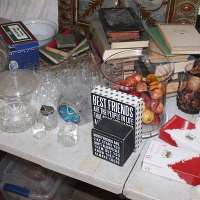 Assortment of vintage home decor, including cut glass bowls, a collection of old books, decorative signs, and holiday items displayed on...