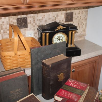 Assortment of vintage items including woven wooden baskets, an antique mantel clock with gold columns, and several old books including a...