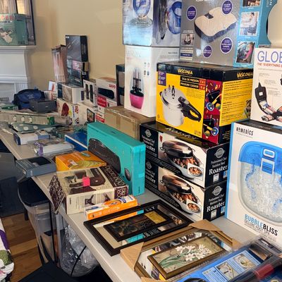 Collection of boxed home goods and electronics, including a HoMedics foot spa, Vasconia pressure cooker, roaster pans, seat cushions, and...