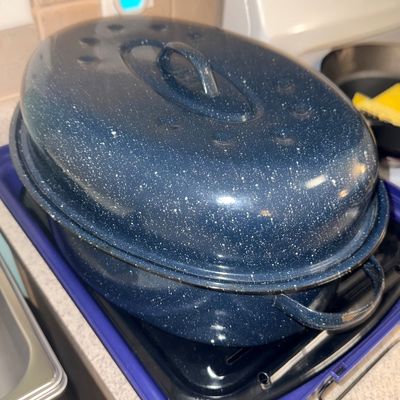 Vintage dark blue speckle enamelware roasting pan with lid, featuring side handles and a domed top.