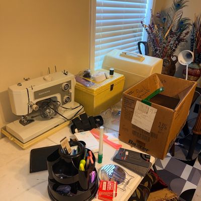 Vintage Kenmore portable sewing machine with hard case, accompanied by a yellow woven sewing basket and assorted craft supplies on a table.