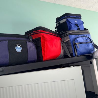 Collection of insulated soft-sided lunch bags and coolers, including Arctic Zone brands, stored on a shelf.
