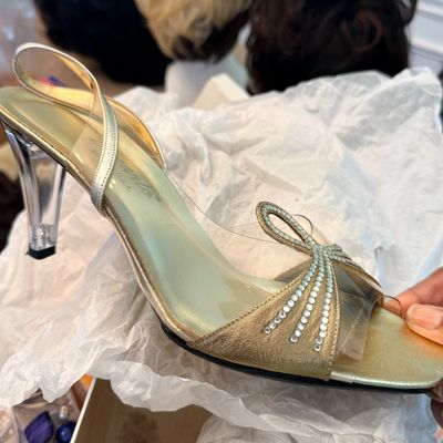 Vintage gold-toned evening sandal featuring a lucite heel, clear vinyl straps, and rhinestone bow embellishments.