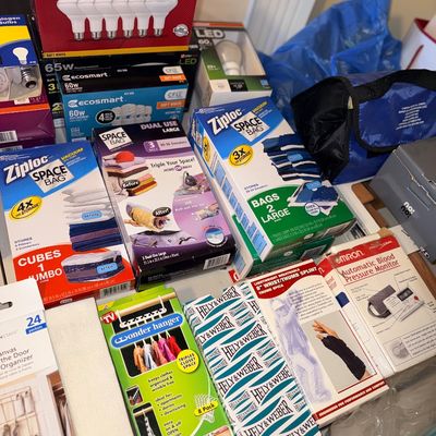 Assortment of household items including LED lightbulbs, Ziploc Space Bags, Wonder Hangers, orthotics, and an Omron blood pressure monitor.