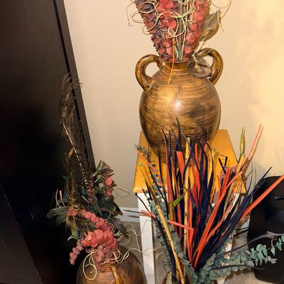 Assortment of decorative ceramic vases filled with dried floral arrangements, including eucalyptus and peacock feathers.