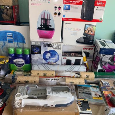 Assortment of boxed household items, electronics, and cleaning supplies including a Lilumia makeup brush cleaner, CyberPower battery...