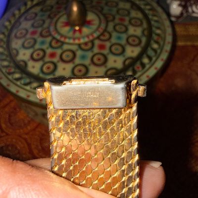 Close-up of a gold-tone mesh watch band or bracelet clasp stamped "ITALY", displaying minor wear and tarnishing.