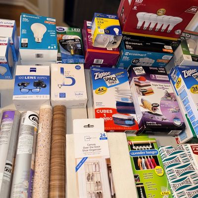 Collection of household goods including LED light bulbs, Ziploc Space Bags, Zeiss lens wipes, shelf liner rolls, and clothing organizers.
