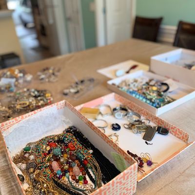 Large collection of vintage costume jewelry, including beaded necklaces, gold-tone chains, brooches, and wristwatches displayed in...