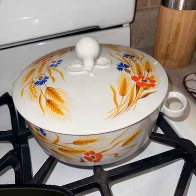 Vintage ceramic covered casserole dish featuring a wheat, poppy, and cornflower motif with a pear-shaped lid handle.