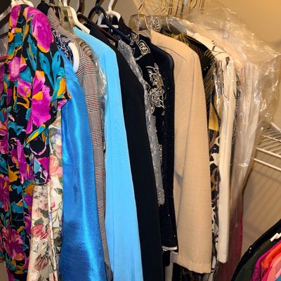 Collection of plus size new & gently owned  women's clothing, including colorful dresses, blazers, and formal wear, hanging on a...