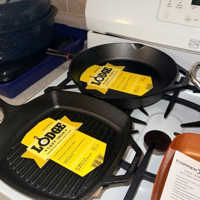 Two brand new Lodge cast iron skillets with original yellow labels, including a 10.5-inch square grill pan and a 12-inch round skillet,...