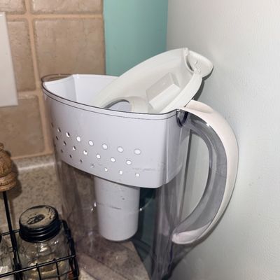 White Brita plastic water filter pitcher with lid, sitting on a kitchen countertop.