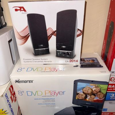 Boxed Cyber Acoustics CA-2014 powered speaker system resting on a Memorex 8-inch portable DVD player in original packaging.