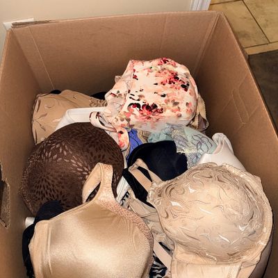 Large cardboard box filled with assorted women's bras in various styles, colors, and patterns.
