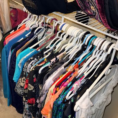Selection of women's plus size new & gently owned  contemporary clothing hanging on a wire closet rack, featuring various...