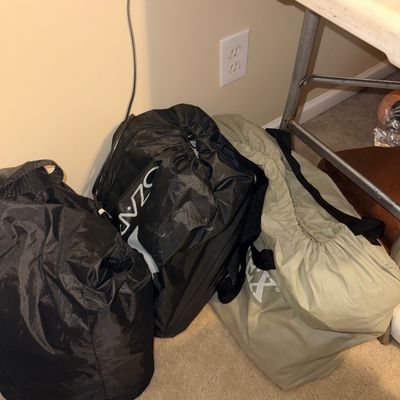 Set of three nylon drawstring equipment and gear bags sitting under a folding table.