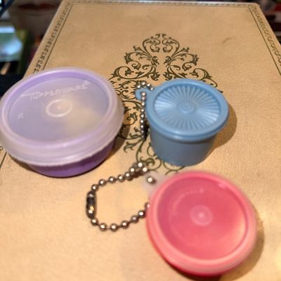 Collection of miniature vintage Tupperware novelty keychains and tiny container in purple, blue, and pink plastic.