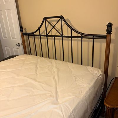 Traditional style metal and wood headboard featuring a dark bronze-finished iron frame with vertical slats, a decorative X-brace top, and...