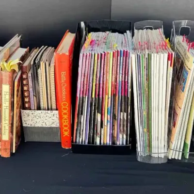 Sale Photo Thumbnail #63: Collection of vintage cookbooks, sewing books, and magazines organized in plastic holders, including titles like McCall's Sewing Book and Betty Crocker's Cookbook.