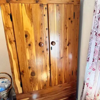 Sale Photo Thumbnail #177: Cedar wardrobe armoire featuring a natural knotty wood grain, arched top, double doors with wooden knobs, and a bottom drawer.