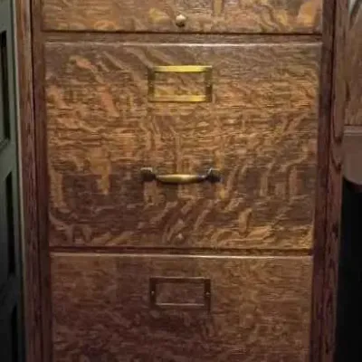Sale Photo Thumbnail #100: Antique tiger oak four-drawer filing cabinet featuring prominent wood grain, brass hardware, and label holders.