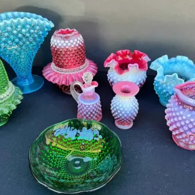 Sale Photo Thumbnail #152: Fenton hobnail glass collection featuring a variety of colorful pieces including vases, fairy lamps, a pitcher, and a small bowl in shades of blue, green, pink, and white.