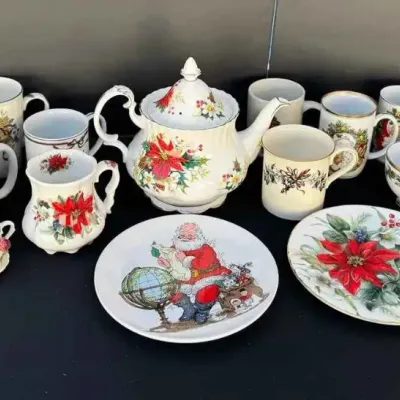 Sale Photo Thumbnail #64: Assorted Christmas-themed tableware, including a teapot, mugs, plates, and decorative tins featuring Santa Claus and poinsettia motifs.