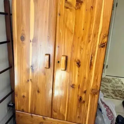 Sale Photo Thumbnail #173: Rustic knotty pine armoire featuring a glossy finish, two doors with wooden pulls, and a single bottom drawer with a scalloped apron.