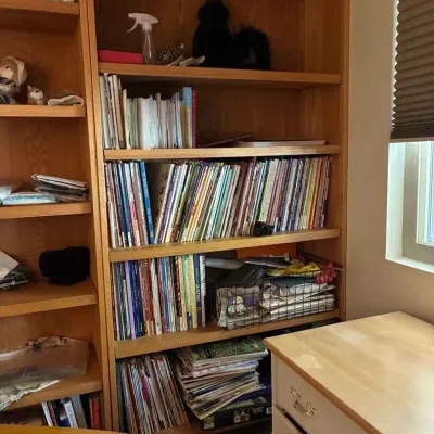 Sale Photo Thumbnail #195: Large oak bookcase filled with books, magazines, and craft supplies, shown alongside a light wood dresser.