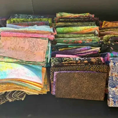 Sale Photo Thumbnail #35: Large assortment of quilting fabric fat quarters in various colorful patterns and batiks, accompanied by several quilting pattern books.