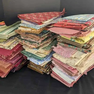 Sale Photo Thumbnail #32: Large assortment of folded quilting fabric quarters and scraps in various colors, floral patterns, and textures.