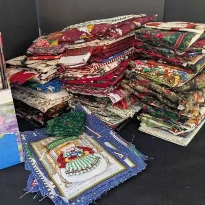 Sale Photo Thumbnail #45: Large collection of Christmas-themed quilting fabric quarters and panels, accompanied by a selection of holiday quilting magazines.