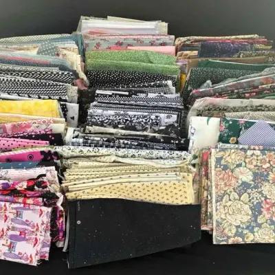 Sale Photo Thumbnail #57: Large collection of folded quilting fabric quarters and remnants in various patterns, including florals, polka dots, and novelty prints.