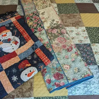 Sale Photo Thumbnail #95: Assorted handmade quilts, including a large floral patchwork quilt and a smaller winter-themed quilt featuring snowman motifs.