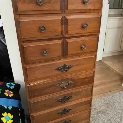 Sale Photo Thumbnail #166: Vintage tallboy dresser featuring a warm wood finish, three upper split-drawer tiers with round pulls, and six lower full-width drawers with ornate brass-tone bail handles.