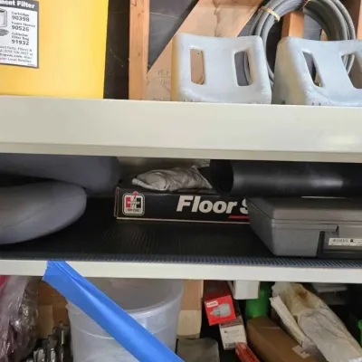 Sale Photo Thumbnail #129: Hurst Floor Shifter box, grey plastic tool case, and other garage items on a metal shelf.