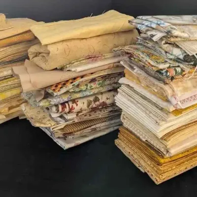 Sale Photo Thumbnail #28: Large collection of folded fabric remnants and quilting quarters in a variety of yellow, cream, and floral patterns.