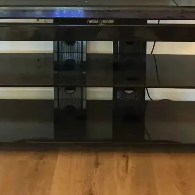 Sale Photo Thumbnail #150: Modern black glass and metal TV stand featuring three tiers of shelving and integrated cable management.