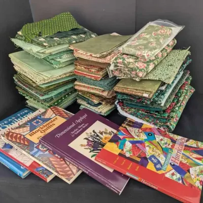 Sale Photo Thumbnail #47: Assortment of quilting books and folded fabric remnants, primarily in shades of green and floral patterns.