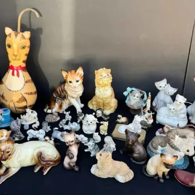 Sale Photo Thumbnail #140: A large collection of vintage cat figurines in various sizes, materials, and poses, including a hand-painted gourd cat, Siamese porcelain figures, and small ceramic miniatures.